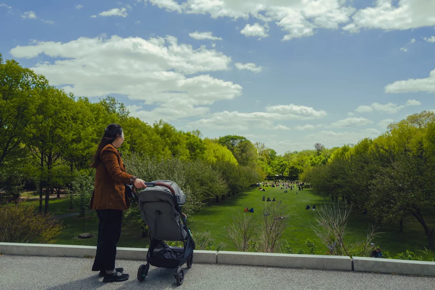 Parents walking with stroller and calm newborn, organized diaper bag visible in soft sunlight