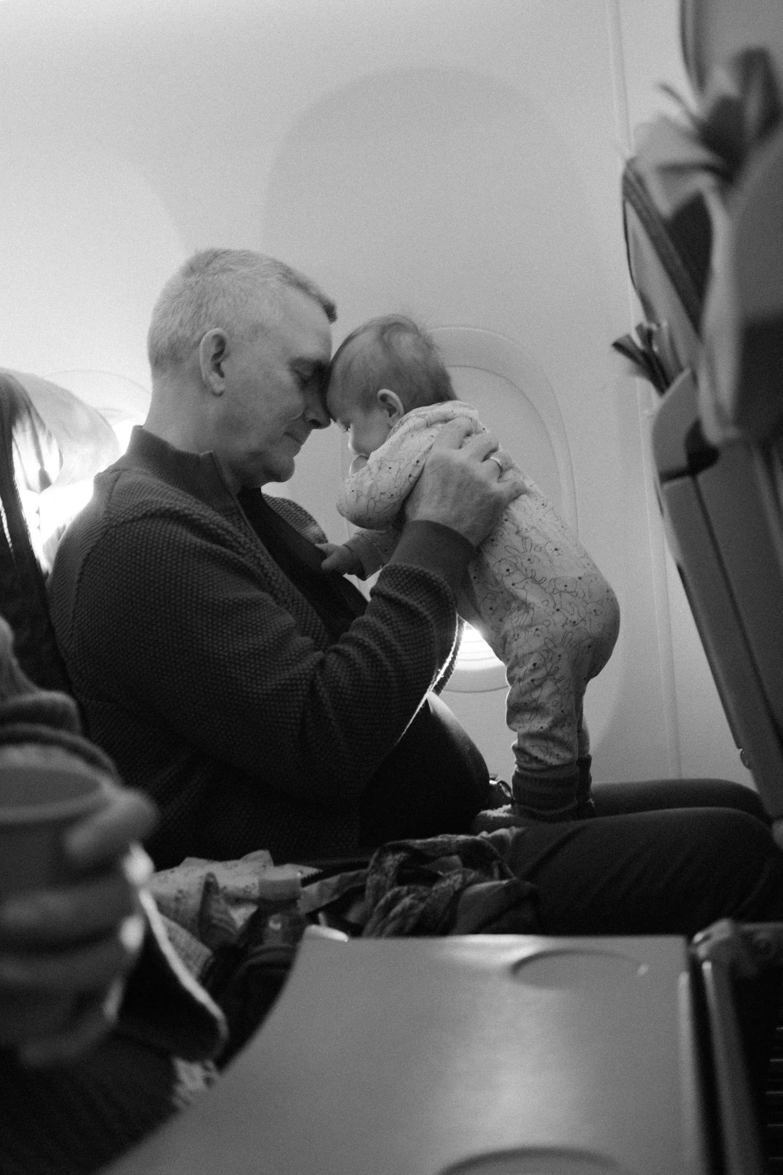 Parent gently holding a baby close in an airplane seat during a flight