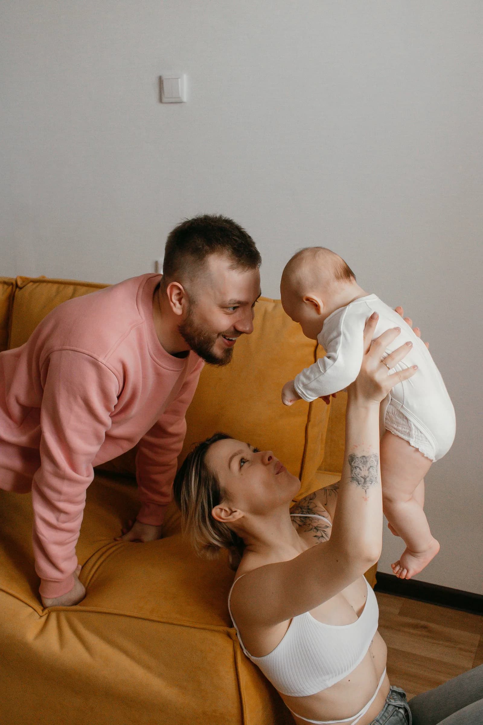 Happy parents holding newborn baby together in hospital room, warm first family moments after birth