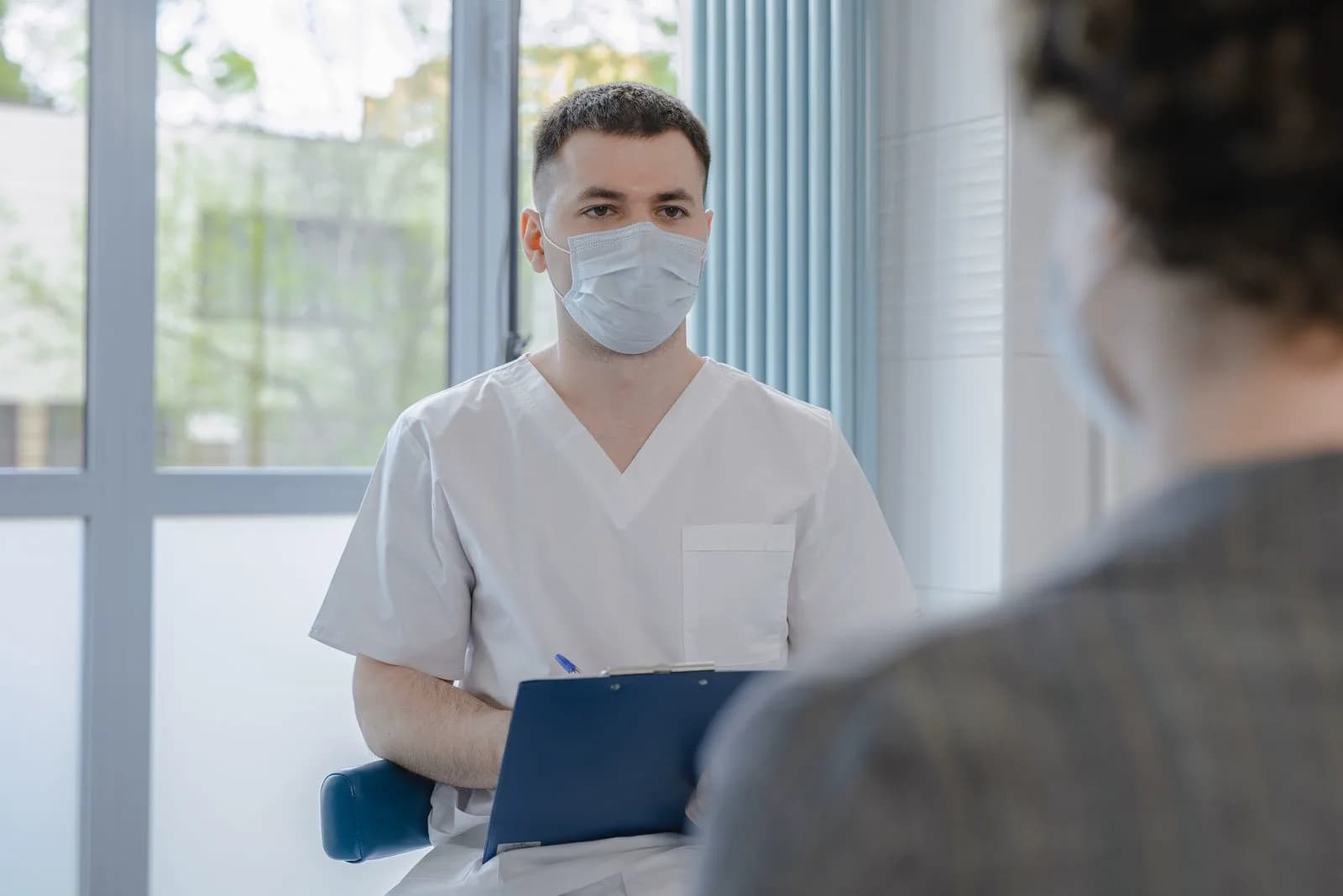 Parent reviewing notes during a pediatrician consultation, preparing questions for the doctor
