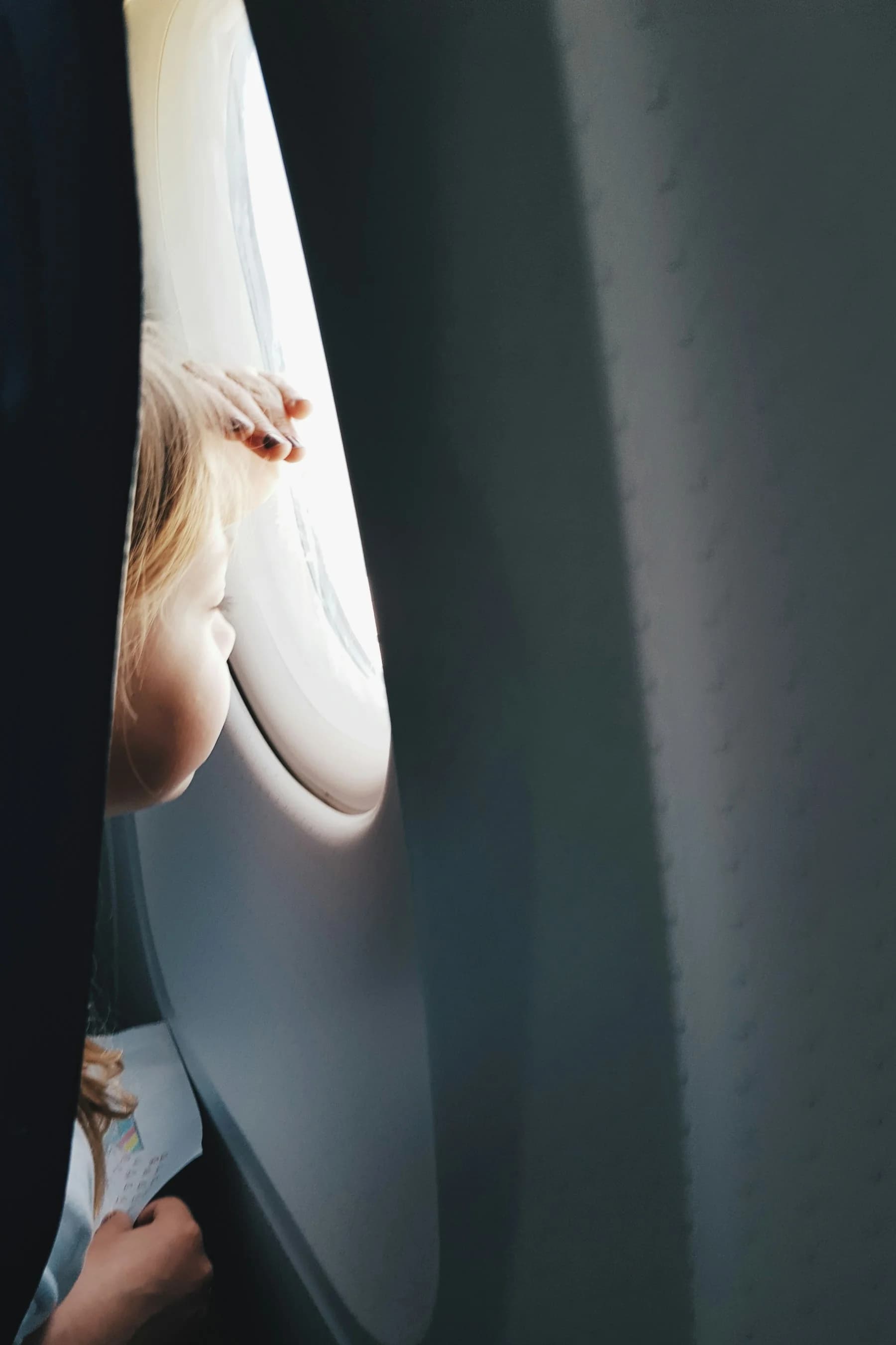 Toddler looking out airplane window seat during a family flight