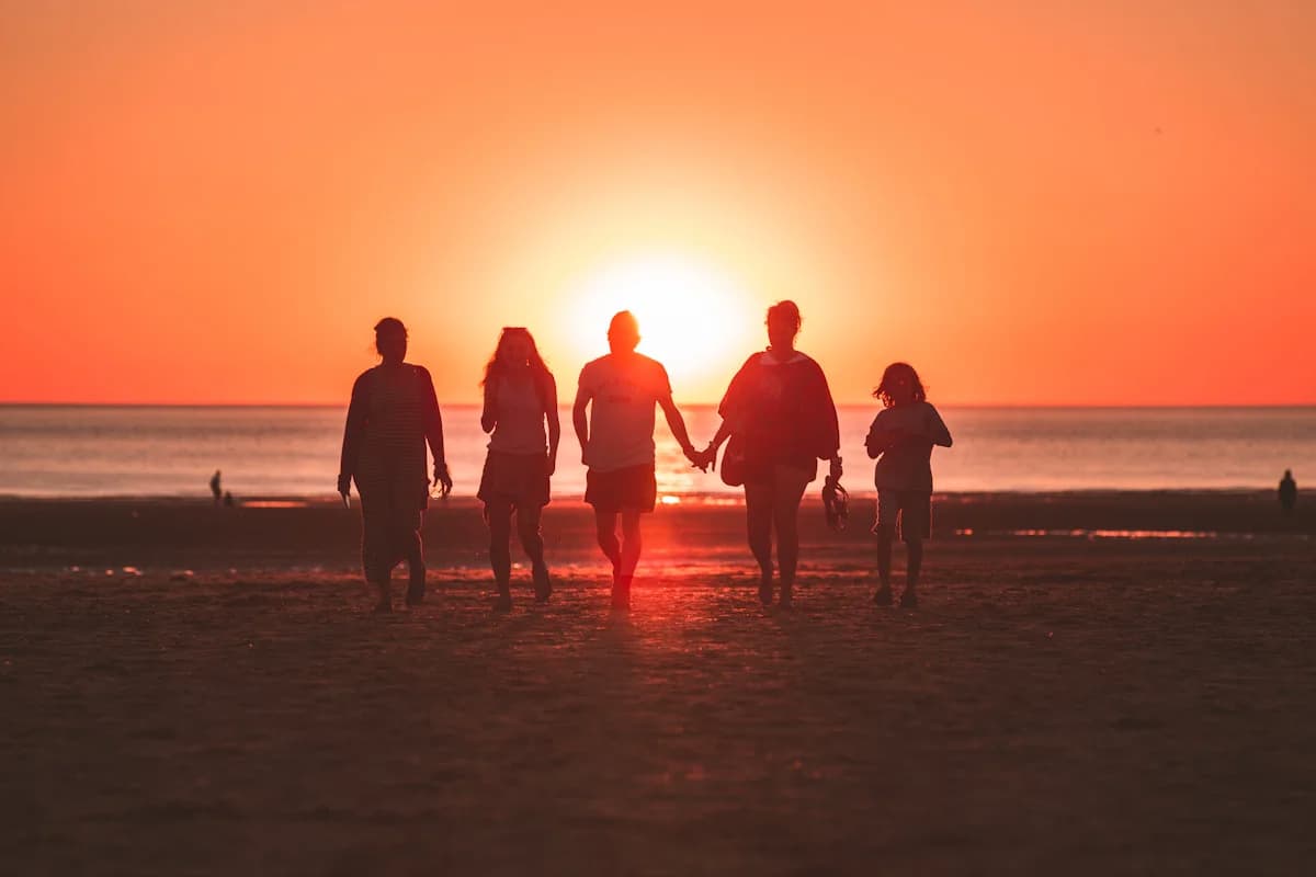 Family silhouette walking along the beach during a golden sunset, relaxed and happy