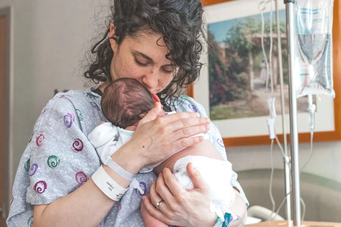 Calm parents holding newborn in soft hospital lighting — emotional first family moments