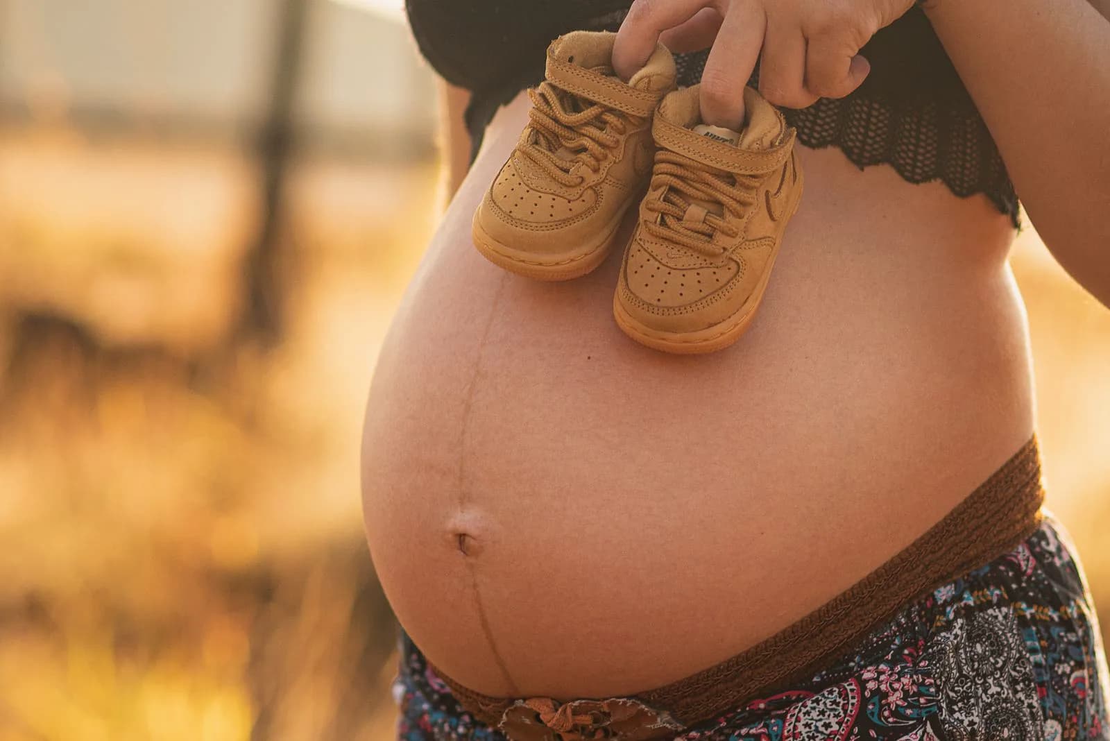 Pregnant woman in third trimester holding baby shoes, preparing for labor and hospital stay