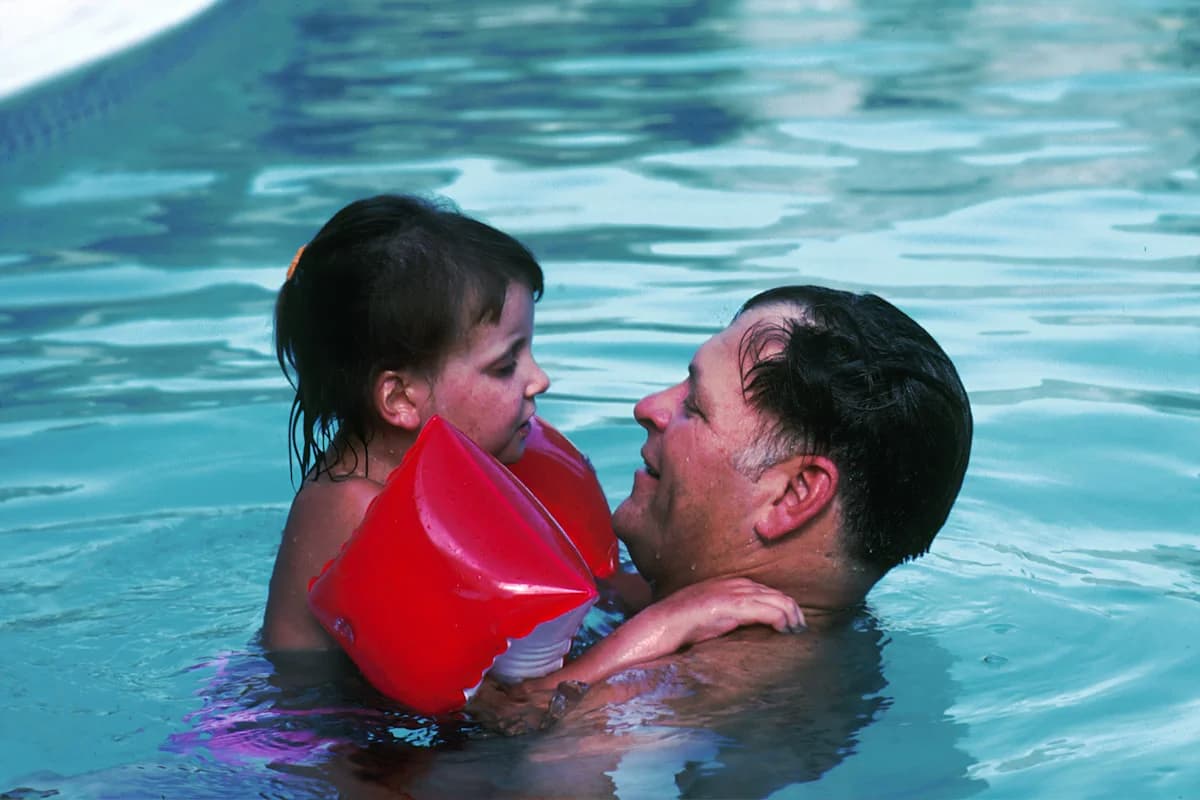 Father holding his young daughter in a swimming pool on a sunny summer day