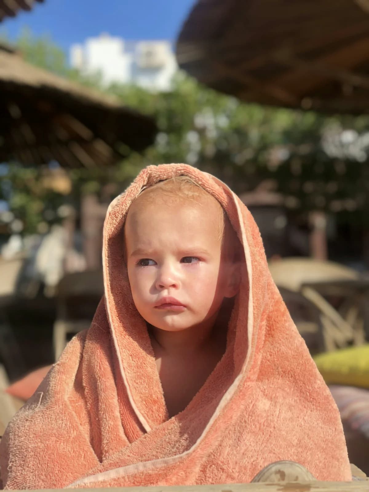 Young child wrapped in a towel after swimming, looking directly at the camera