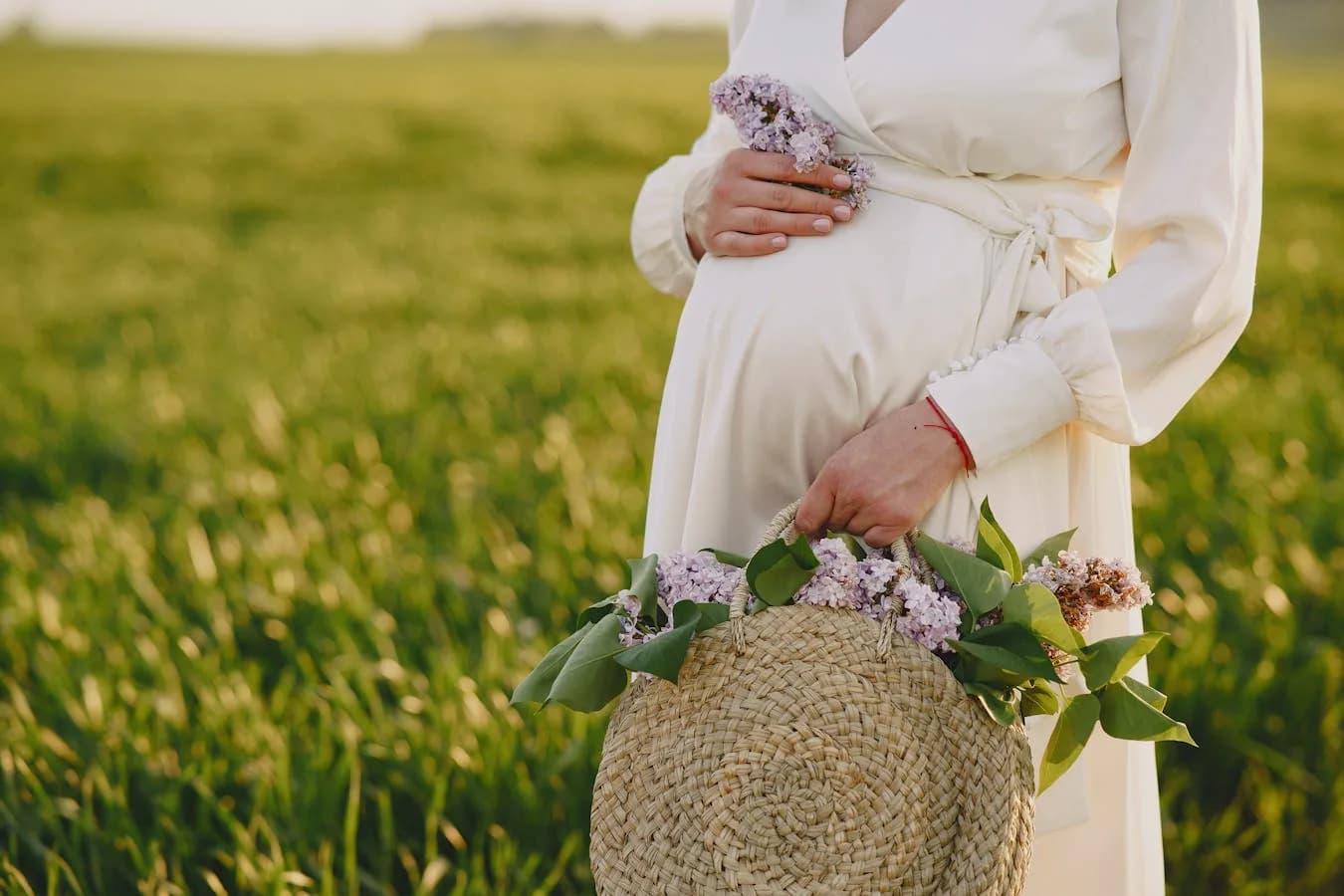 Pregnant mom sitting beside packed hospital bag with folded baby clothes nearby